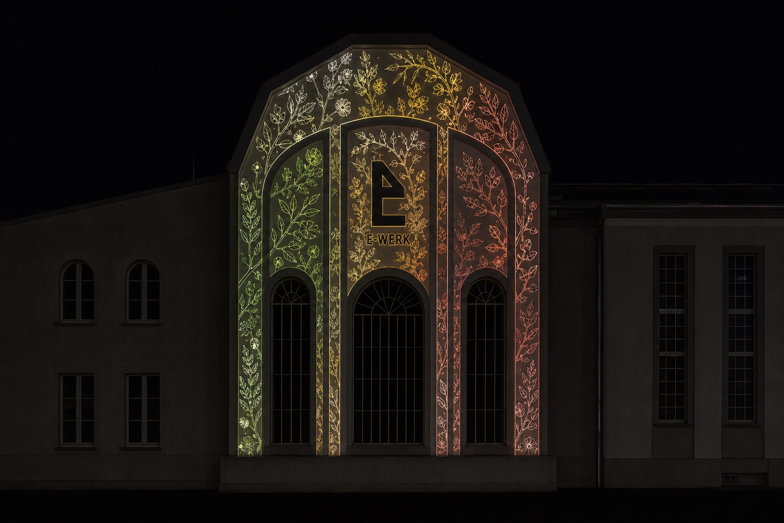 Filigrane Pflanzenprojektion in Grün und Kupfer auf dem Giebel des E-Werks Freiburg